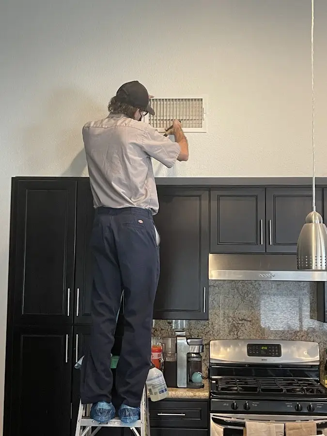 Technician inspecting an air vent during HVAC service in Cresaptown